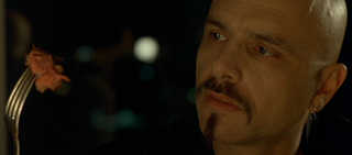 Joe Pantoliano as Cypher in The Matrix, a forkful of steak halfway to his mouth